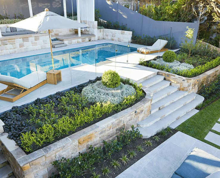 Pool area landscaping with tropical plants and paving in Sydney